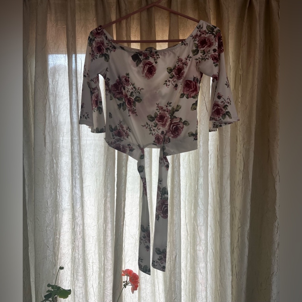 Small off the shoulder floral top with a tie at the bottom. Top is cropped